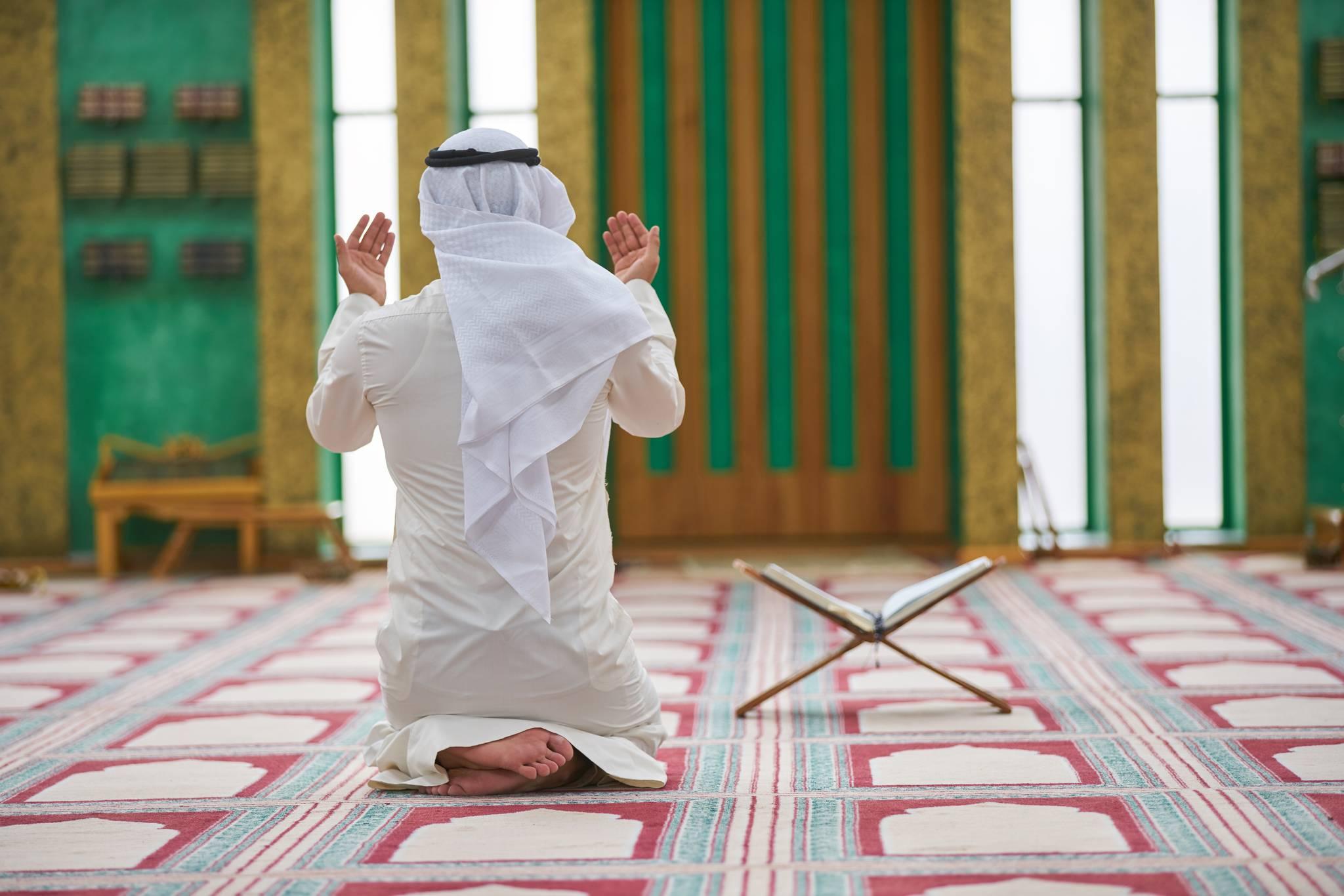 homme islamique prie dans une mosquée avec le Coran