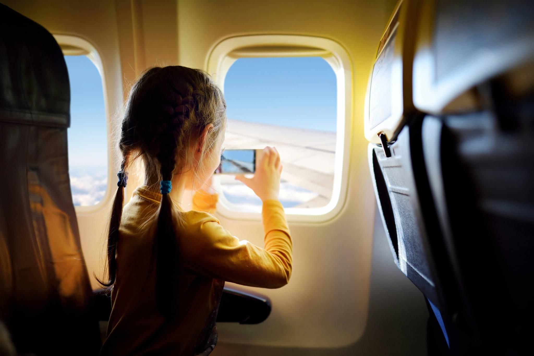 fille prend des photos avec un téléphone depuis la fenêtre de l'avion